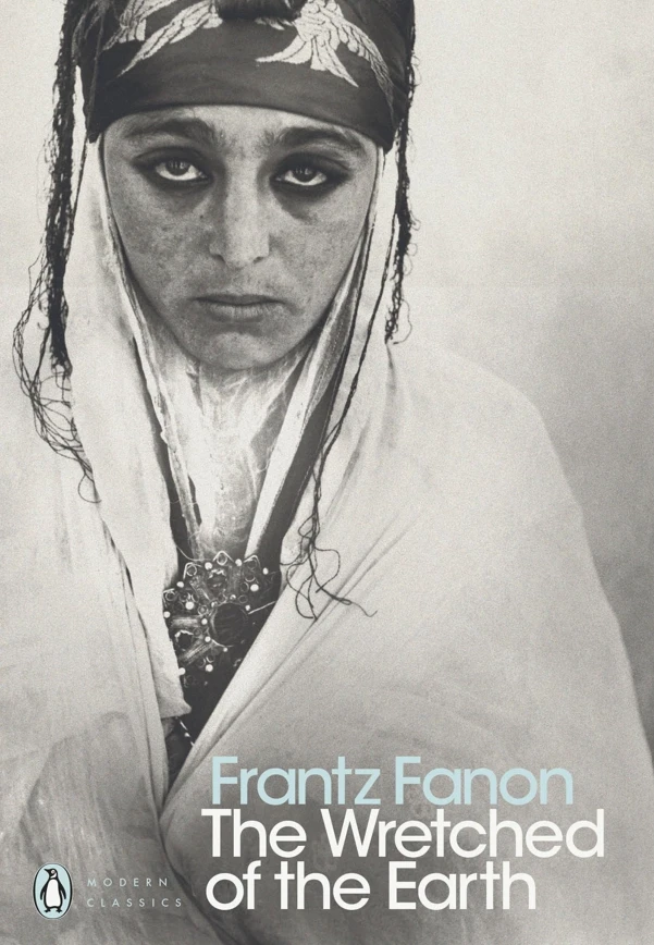 The cover of "The Wretched of the Earth" by Frantz Fanon (Penguin Modern Classics), featuring the full black-and-white photograph of a woman in a headscarf and jewellery looking directly at the camera.